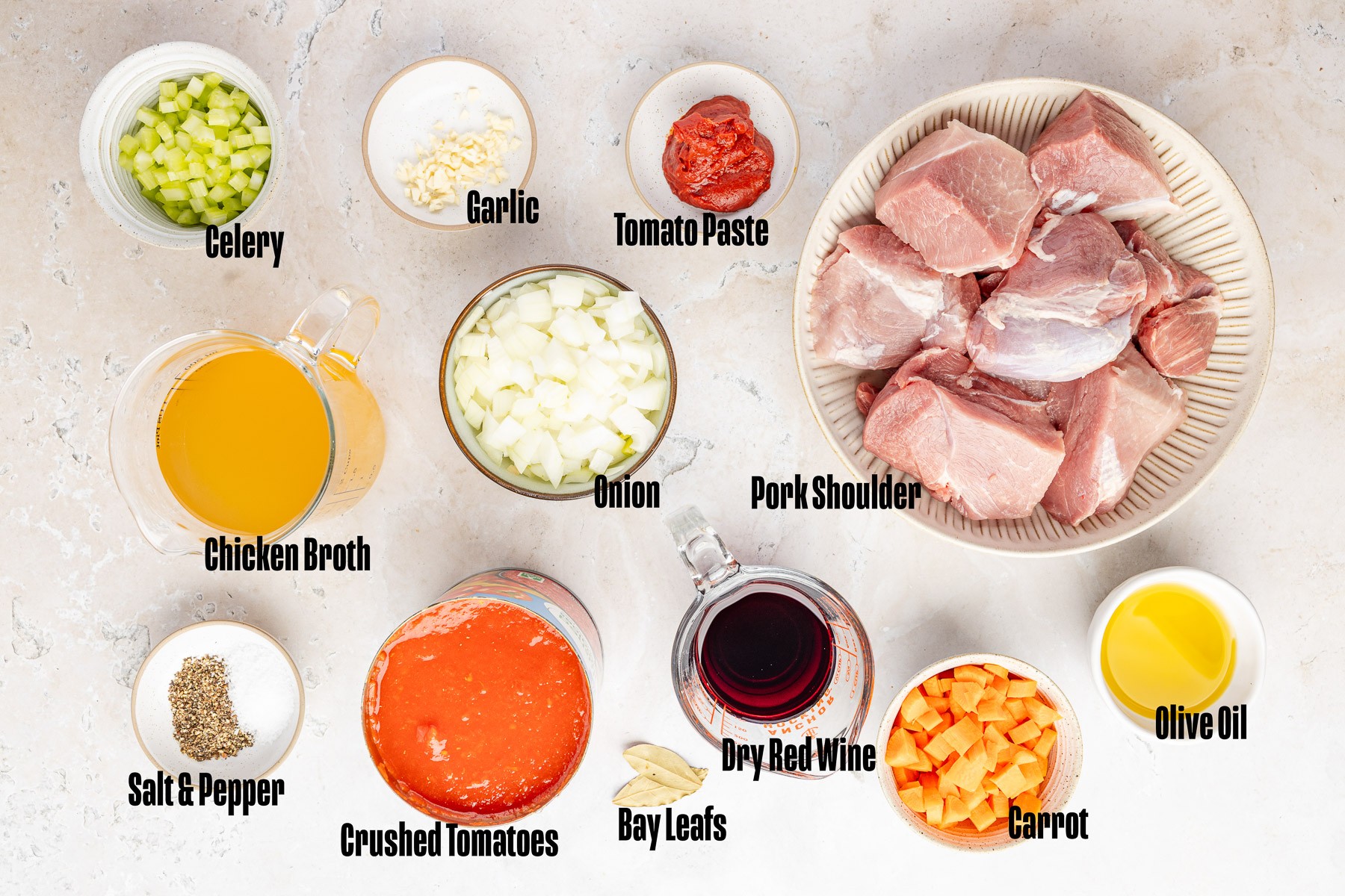 Ingredients to make this ragu with pork shoulder in bowls on a table.