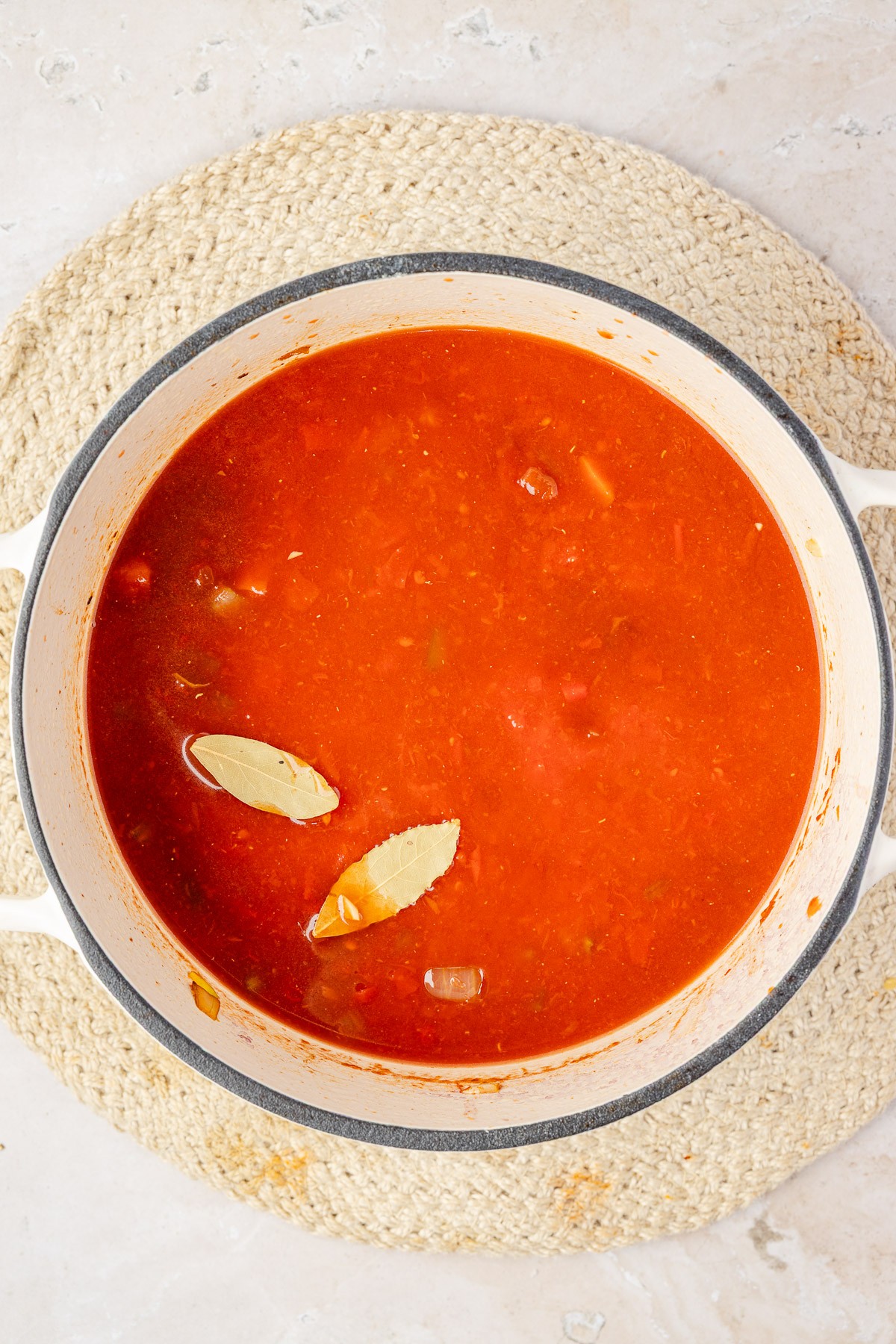 Chicken broth, crushed tomatoes, and bay leaves added to the dutch oven.