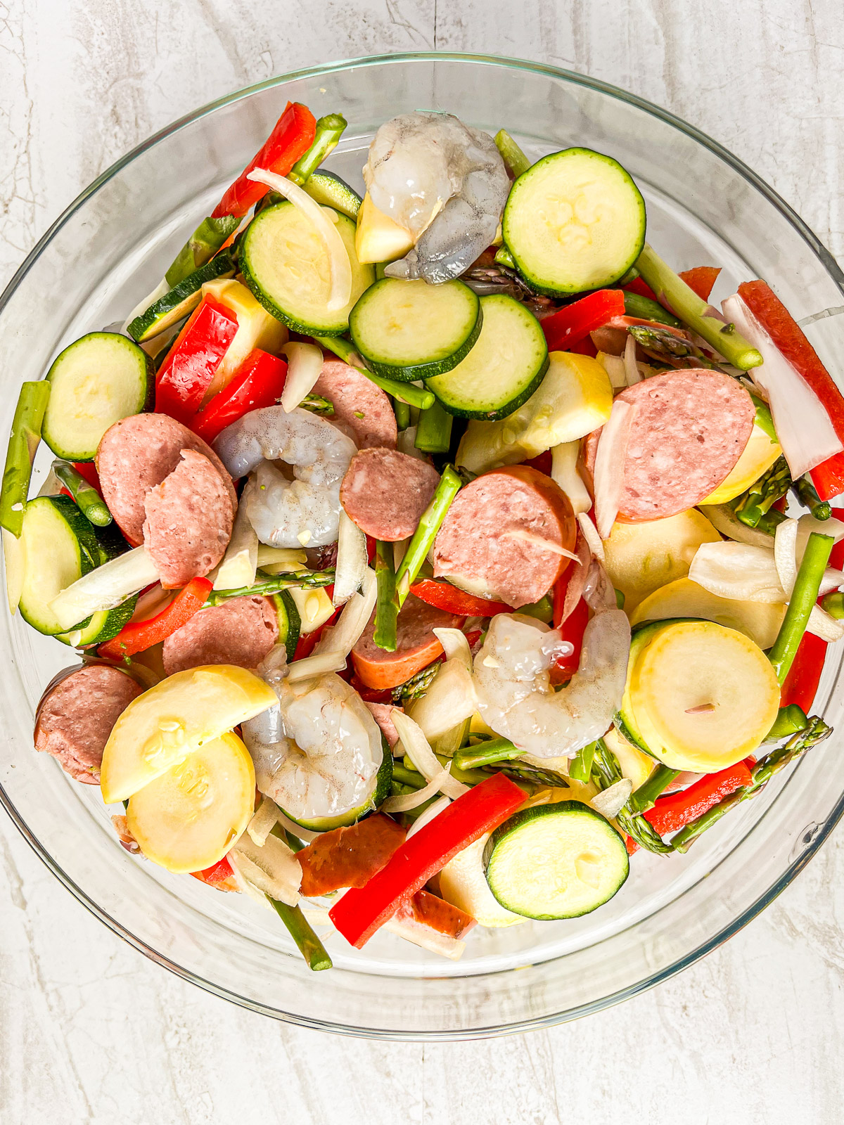 Vegetables and meats for cajun sausage and shrimp in a mixing bowl.