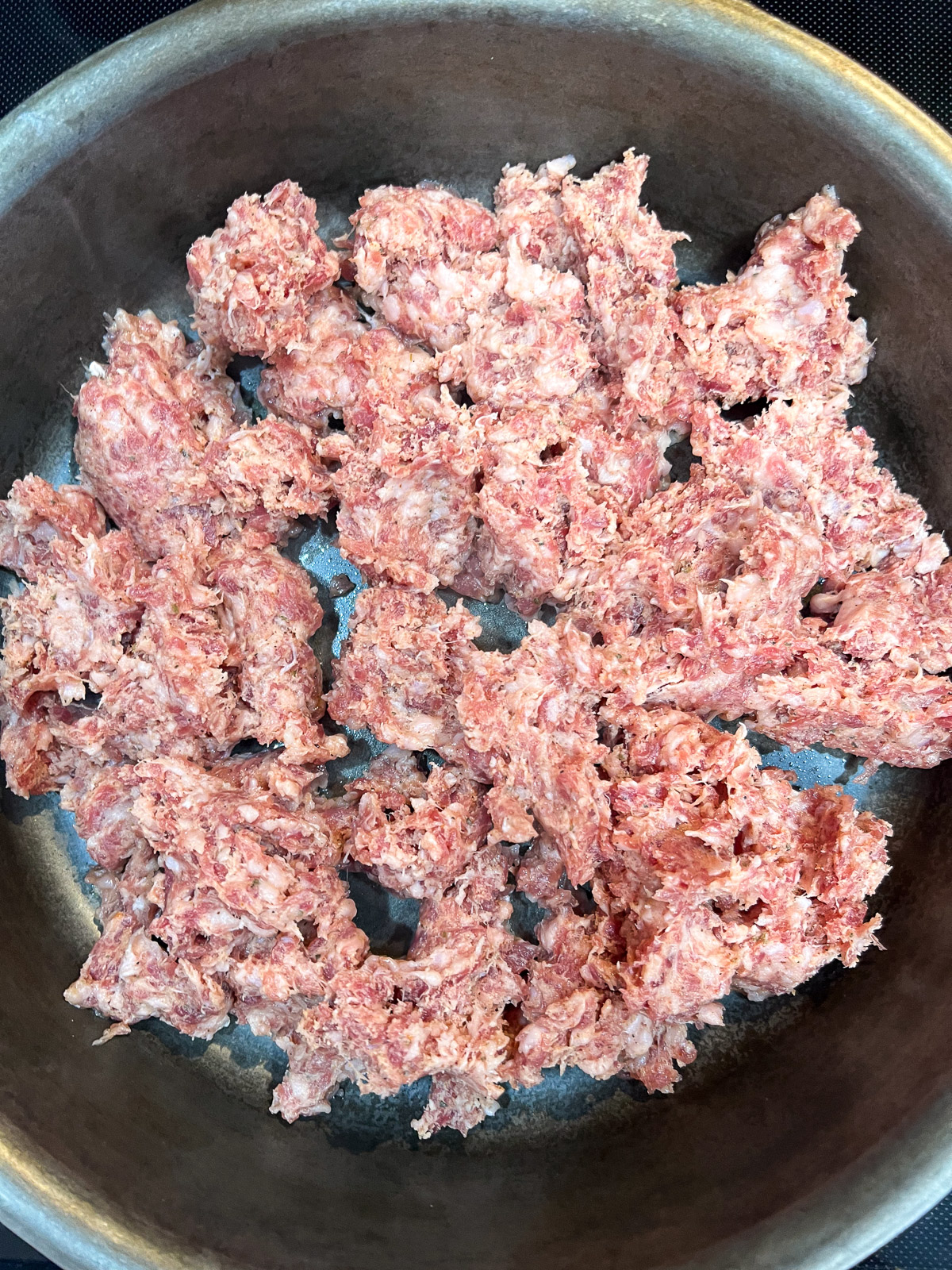 Breakfast sausage being cooked in a cast iron skillet for easy sausage gravy.