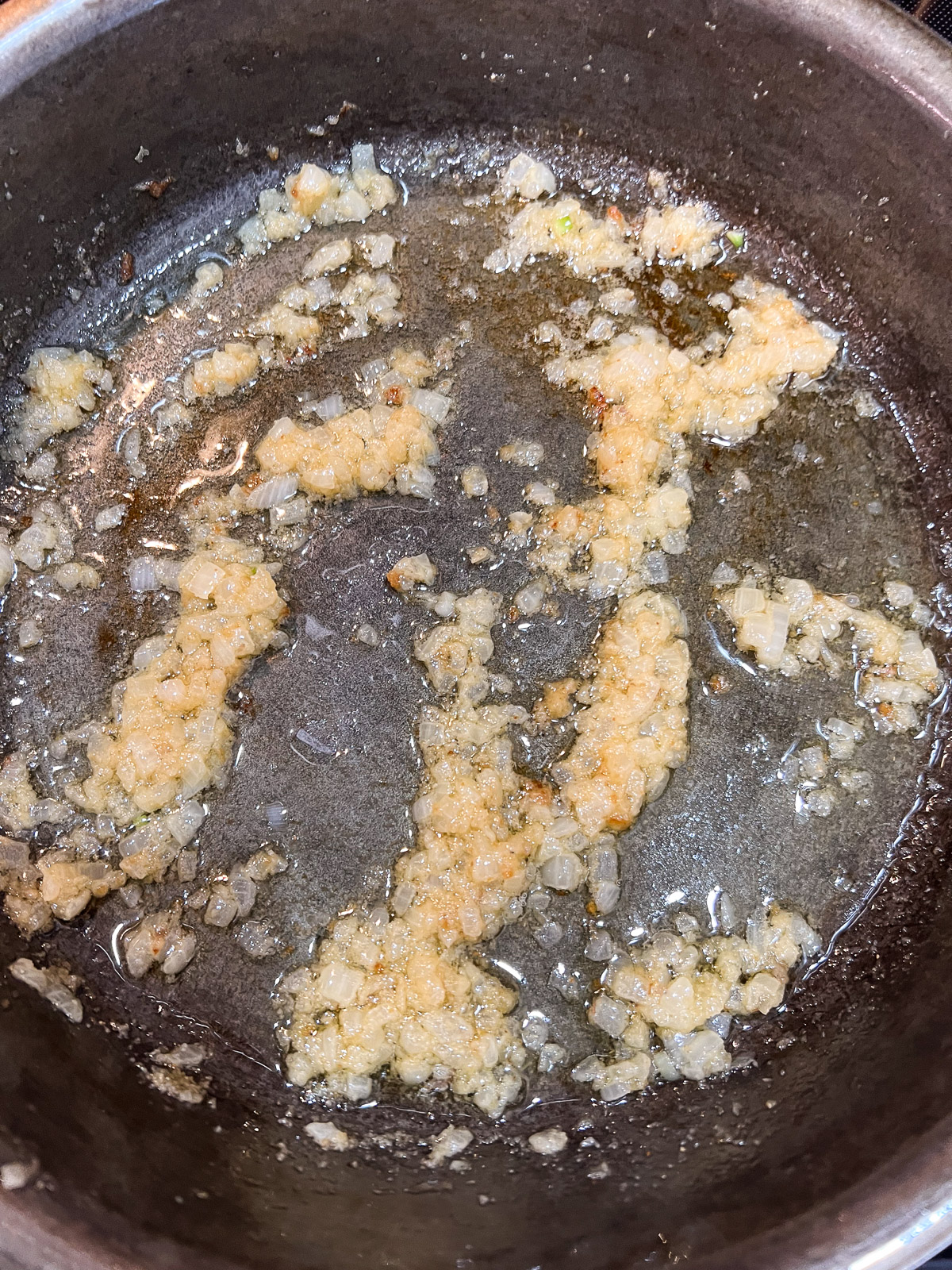 Onions and butter being cooked in a cast iron skillet for sausage gravy.