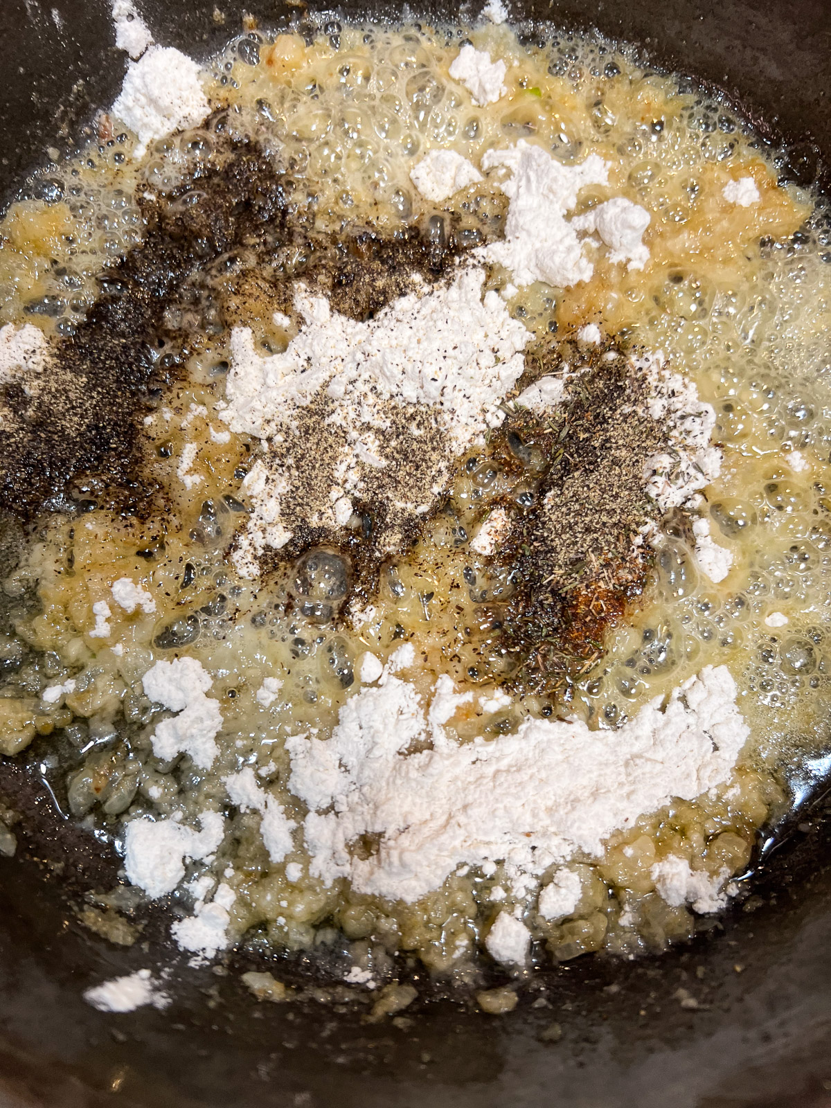 Flour added to the skillet of onions and butter to make a roux for sausage gravy.