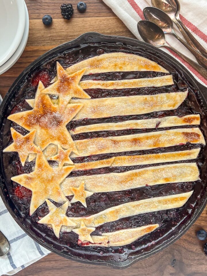 Cast iron skillet berry cobbler with a stars-and-stripes pie crust topping dusted with sugar