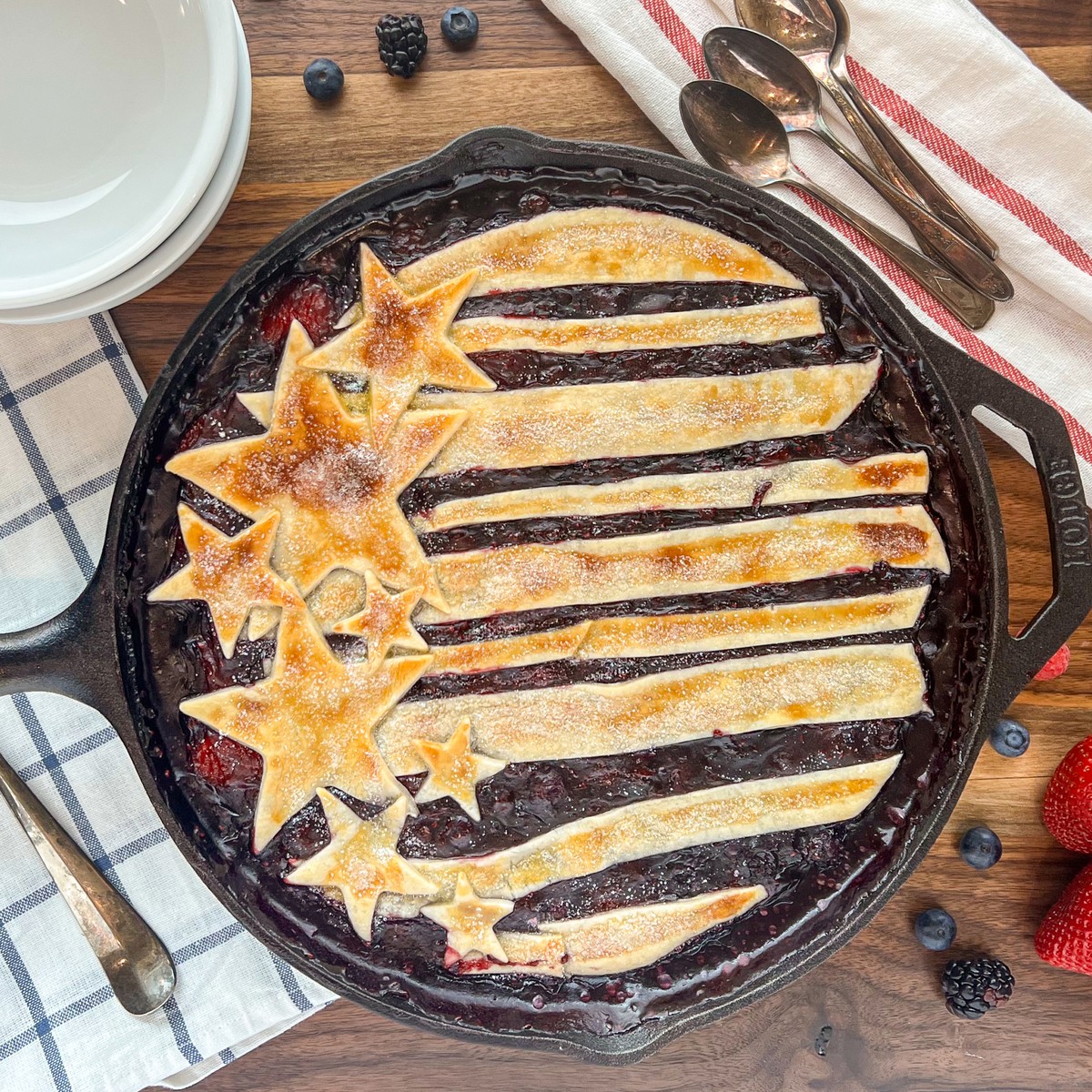 Cast iron skillet berry cobbler with a stars-and-stripes pie crust topping dusted with sugar