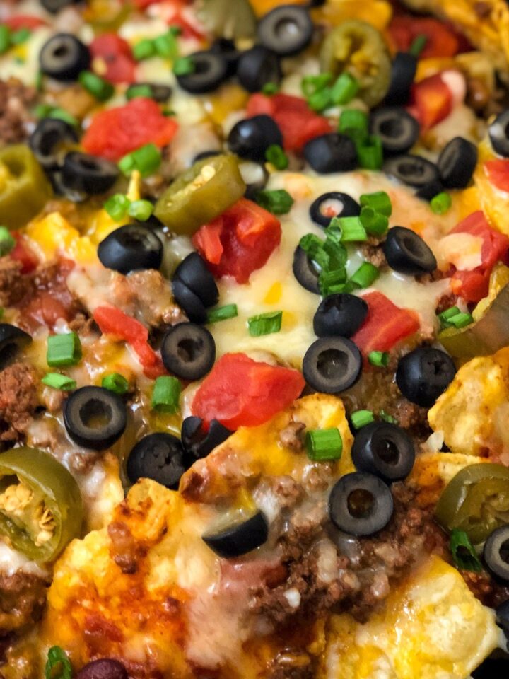 Loaded cast iron skillet nachos with jalapenos, black olives, tomatoes, and melted cheese