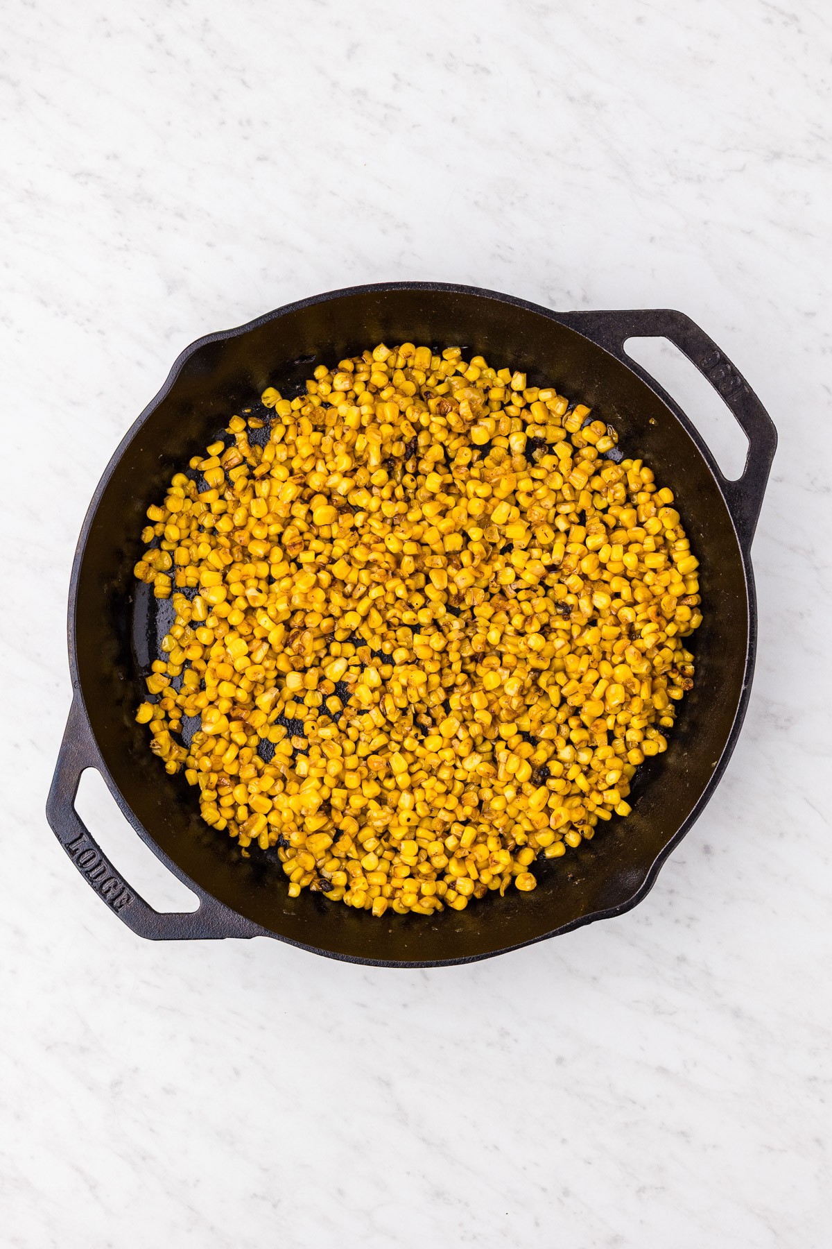 Corn developing golden caramelized spots in the cast iron skillet