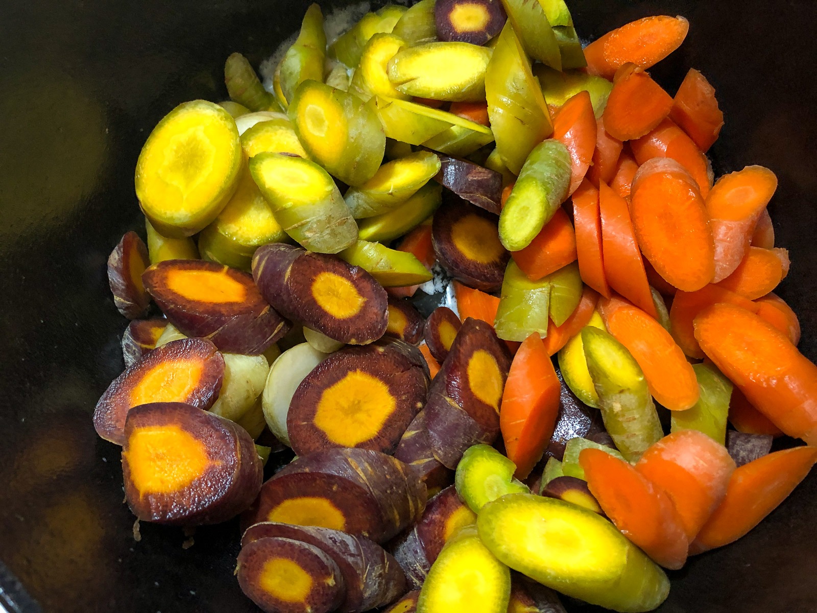 Sliced carrots tossed in melted butter in a Dutch oven.