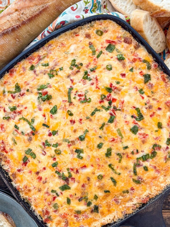 Hot pimento cheese dip baked in a cast iron skillet with golden bubbly top
