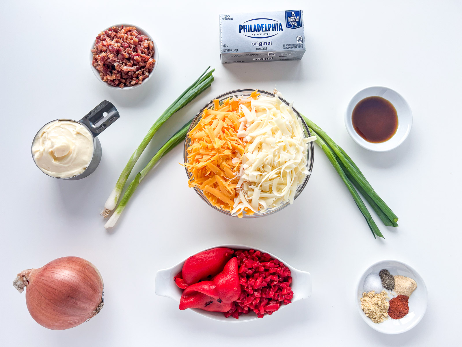 Ingredients to make hot pimento cheese dip: cream cheese, cheddar, Monterey Jack, pimentos, roasted red peppers, bacon, mayo, and seasonings