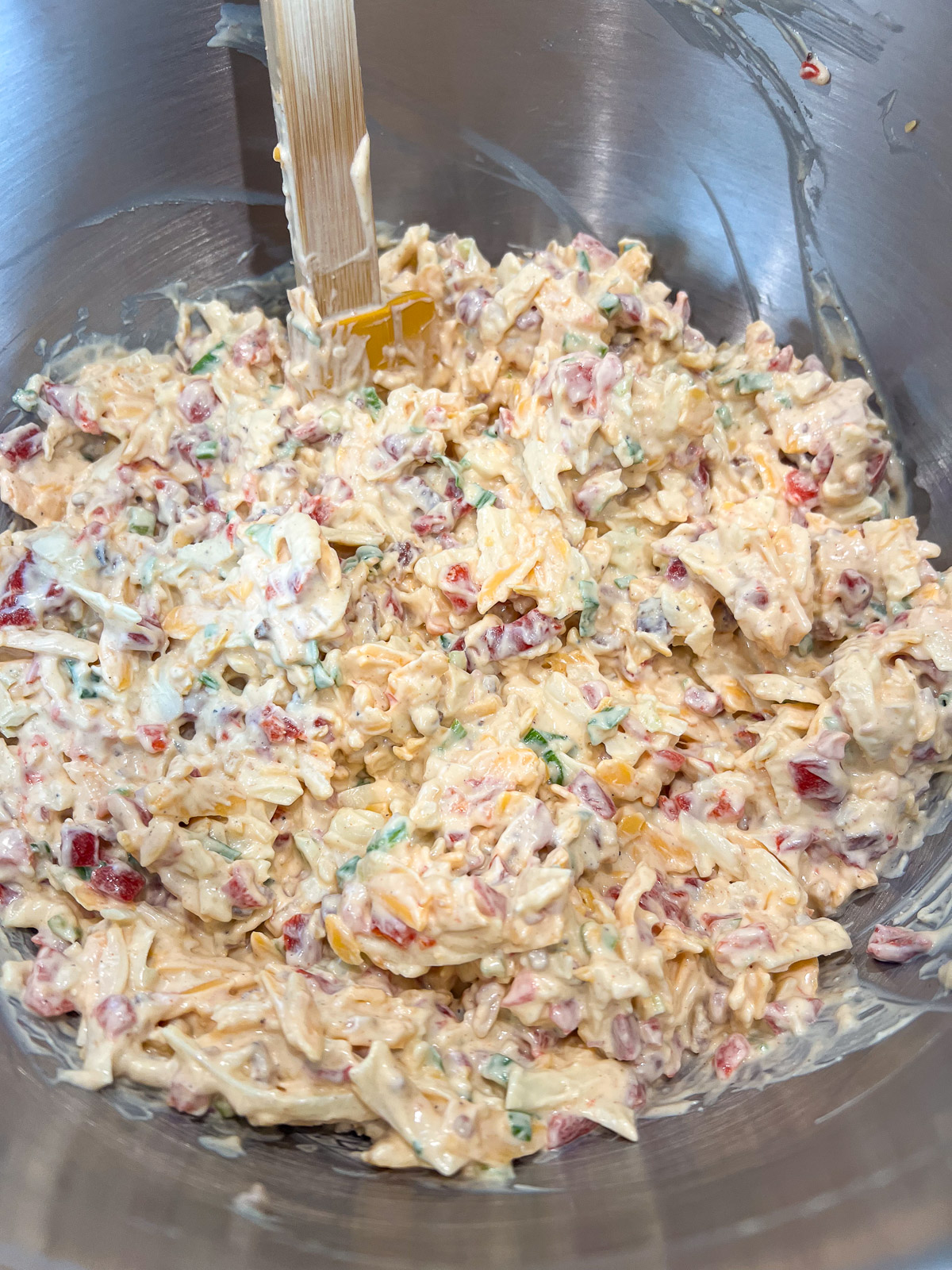 Shredded cheddar and Monterey Jack cheese being stirred into the pimento cheese mixture