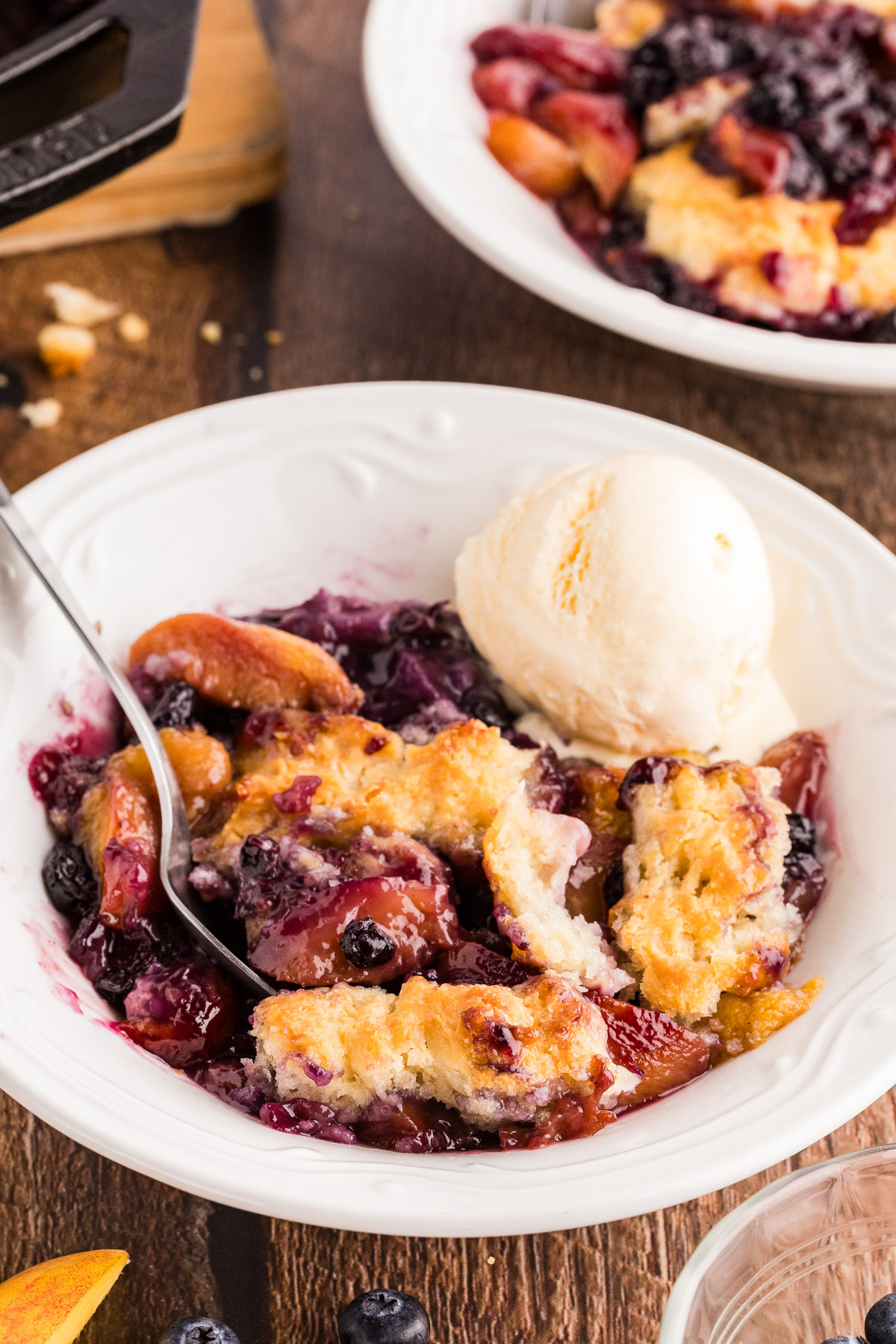 Peach blueberry cobbler served in a bowl with vanilla ice cream