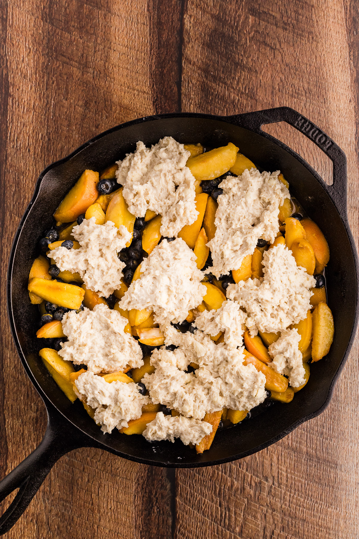 Biscuit dough dropped over peach blueberry filling in a cast iron skillet