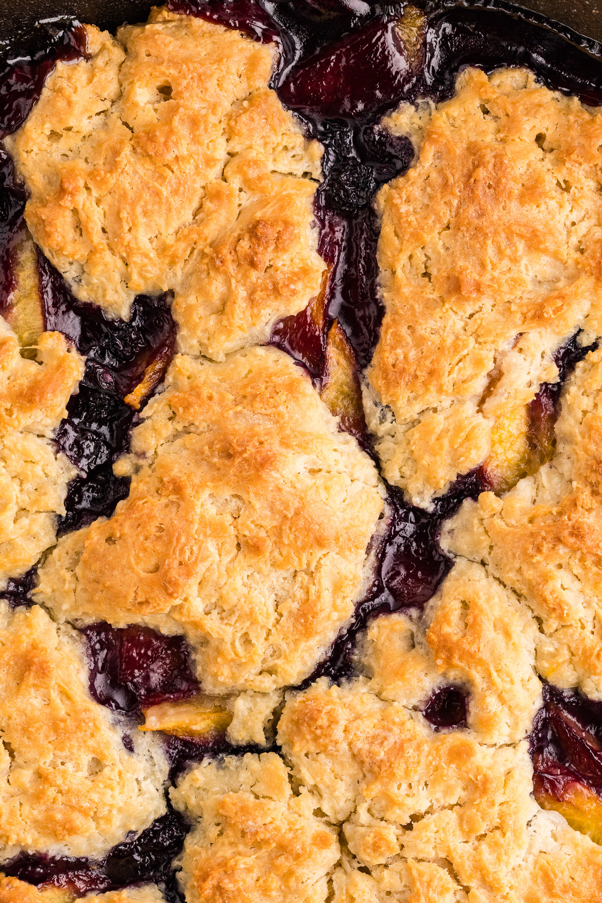 Close-up of golden biscuit topping on peach blueberry cobbler
