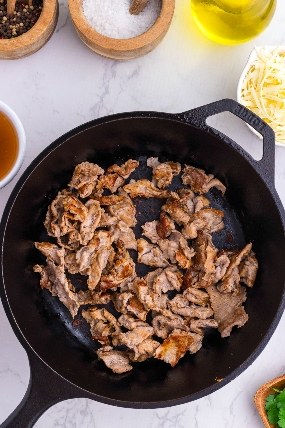 Thinly sliced beef searing in a cast iron skillet