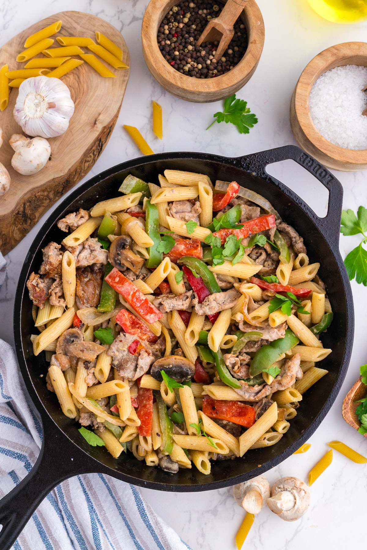Philly cheesesteak pasta in a cast iron skillet topped with fresh parsley