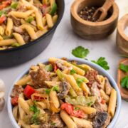 Philly cheesesteak pasta served in a blue bowl with parsley garnish