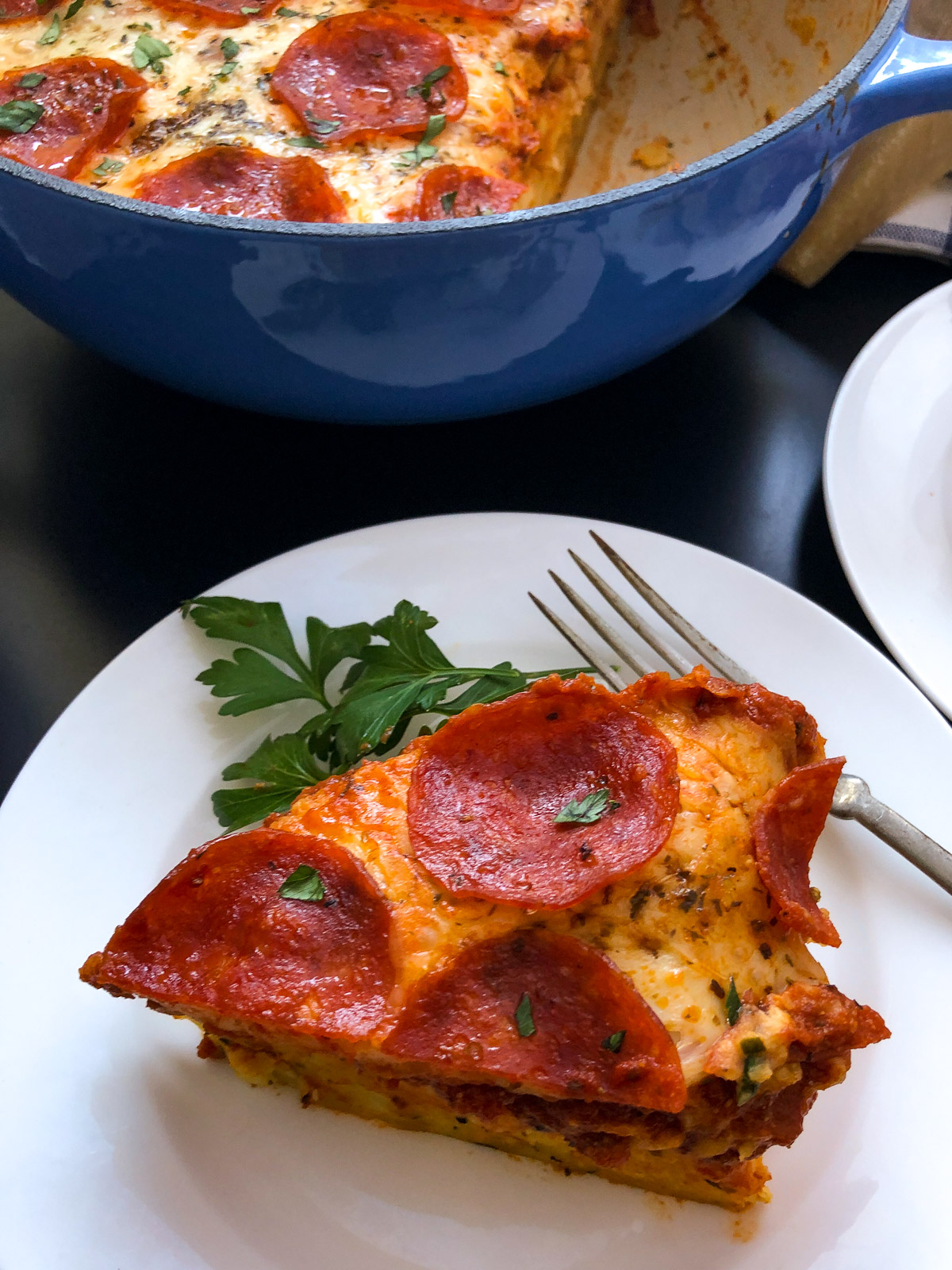 A slice of pizza pasta bake on a plate showing the firm pasta base and melted cheese topping.