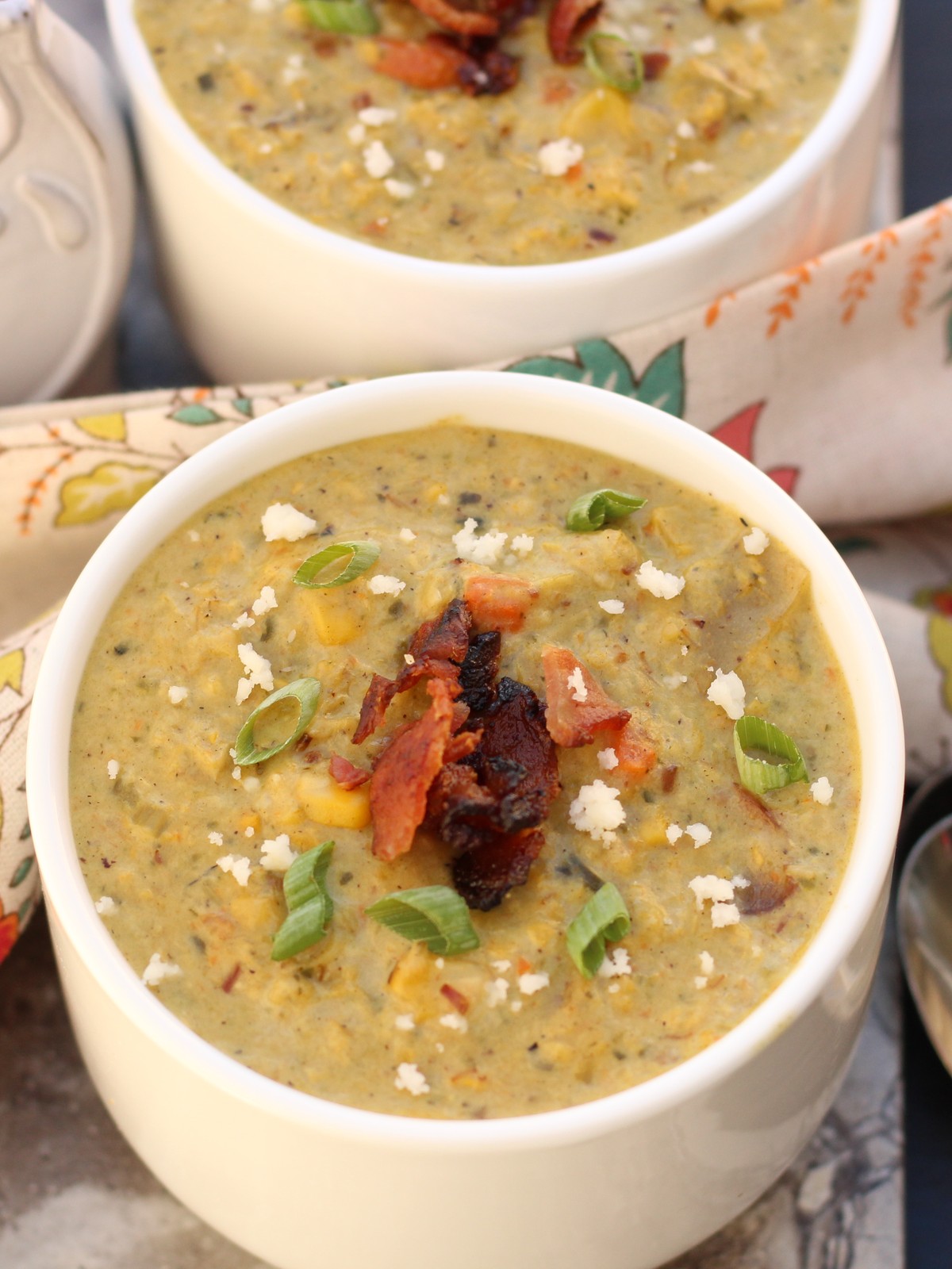 Roasted poblano corn chowder in a white bowl topped with crumbled cheese and roasted peppers