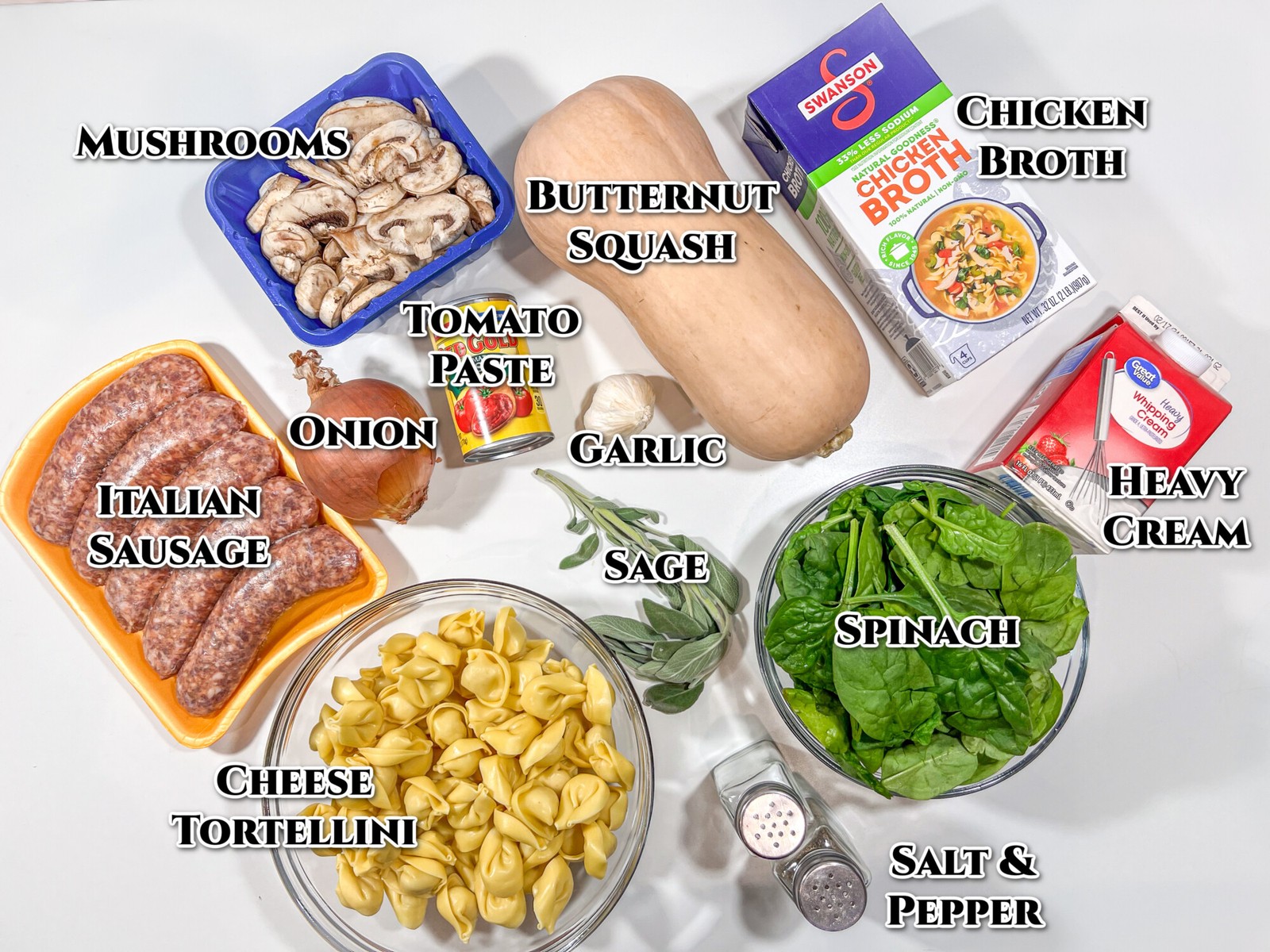 Labeled image of ingredients for the recipe: mushrooms, butternut squash, chicken broth, cream, spinach, salt, pepper, sage, garlic tomato paste, onion, cheese tortellini, and Italian sausage.