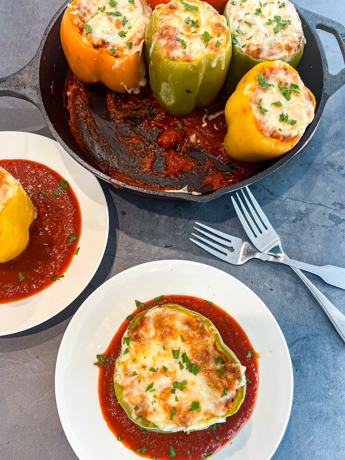 A single sausage stuffed pepper on a white plate with pasta sauce.