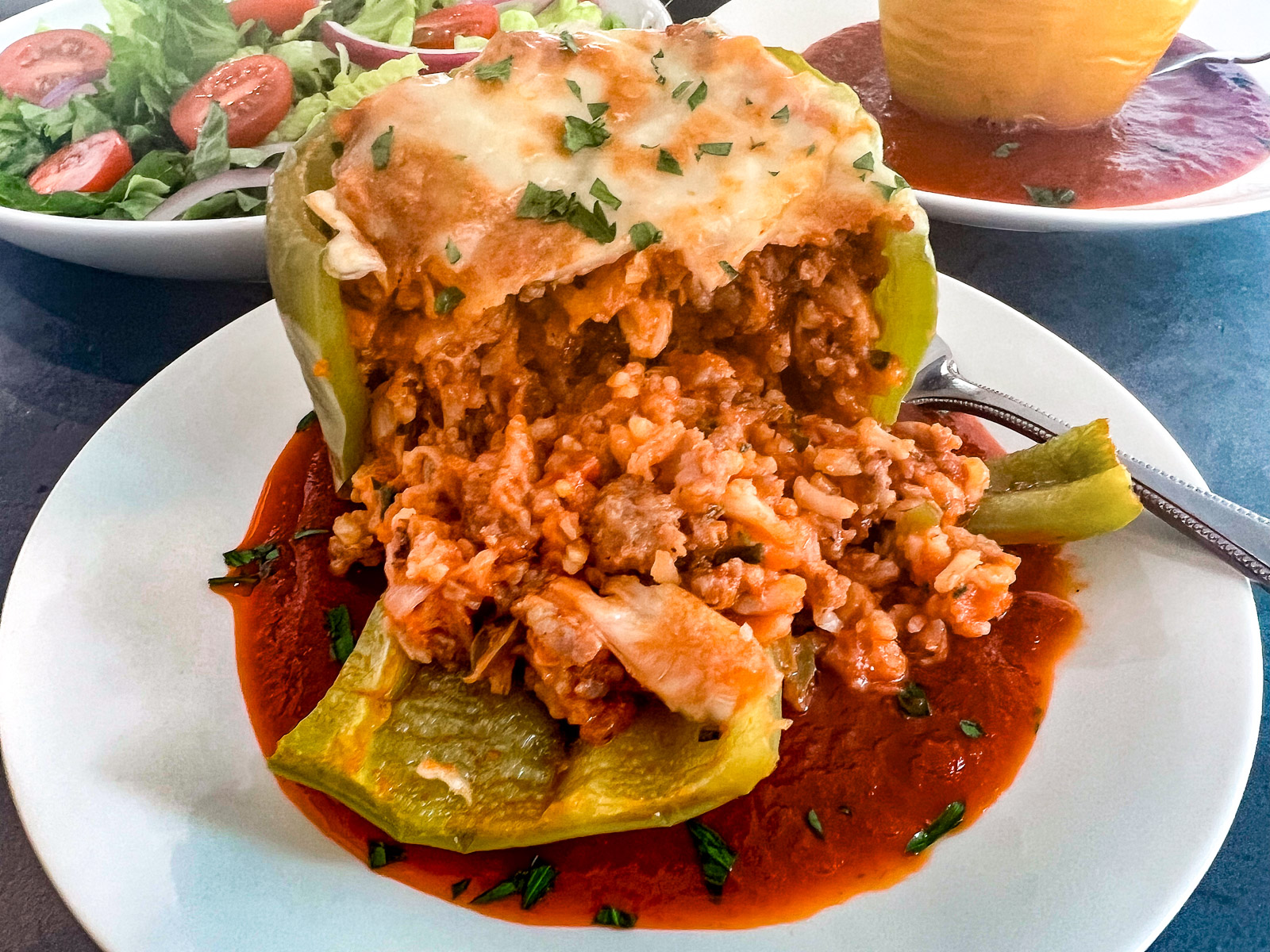 Freshly baked sausage stuffed peppers in a cast iron skillet with melted cheese on top.