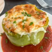 Sausage stuffed pepper on a white plate with marinara sauce