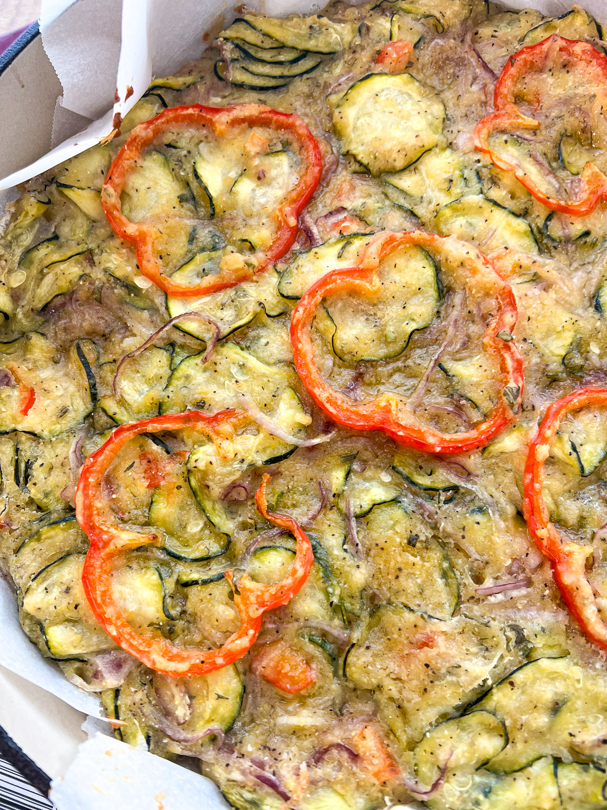 Close-up of golden-brown baked scarpaccia top showing crispy edges and red bell pepper rings