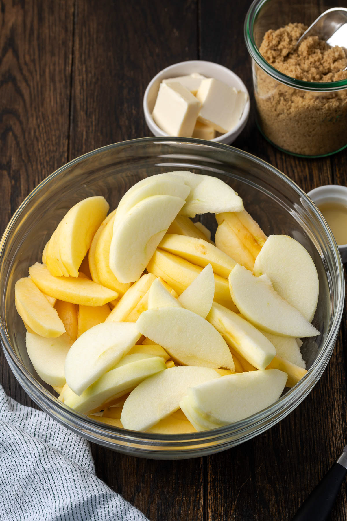 sliced apples in a glass bowl with butter and brown sugar ready for cast iron cinnamon apples