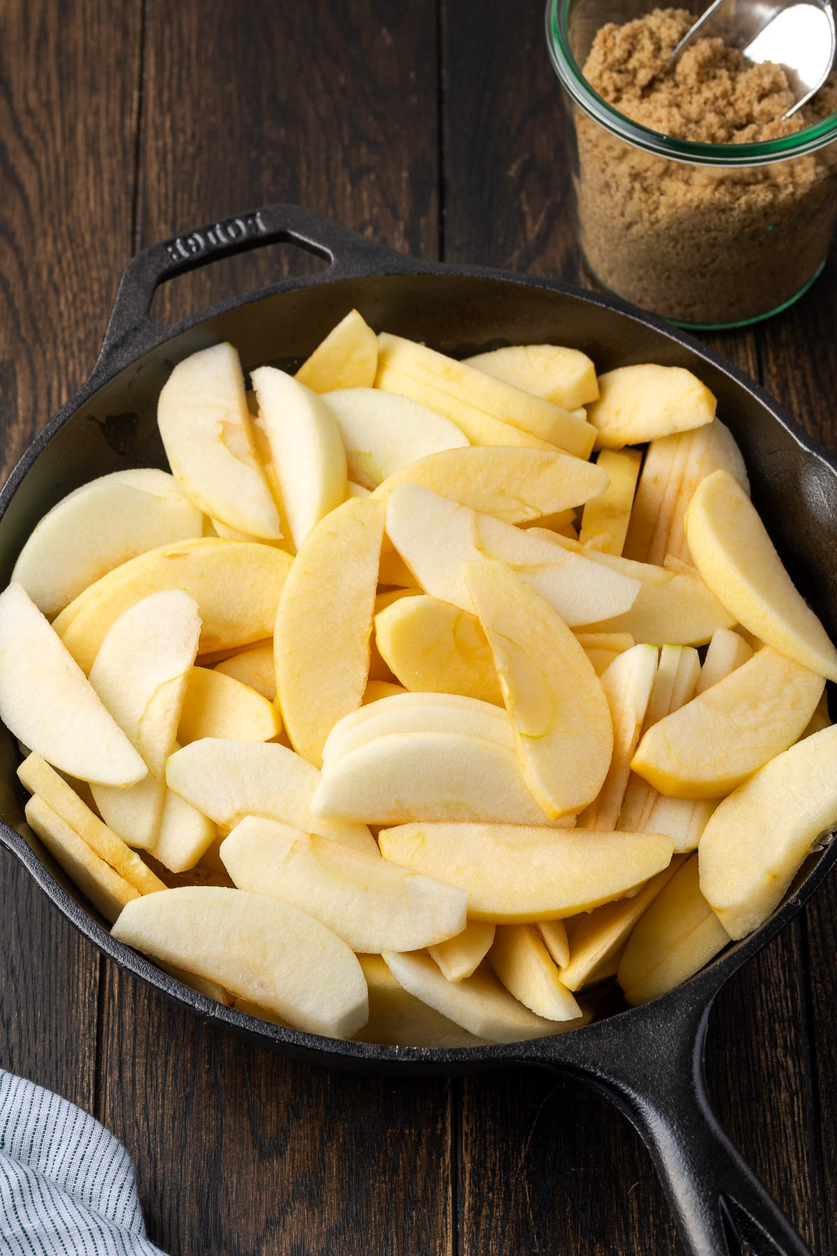 raw apple slices added to the brown sugar glaze in a cast iron skillet