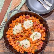 Sweet potato breakfast hash topped with eggs in a cast iron skillet