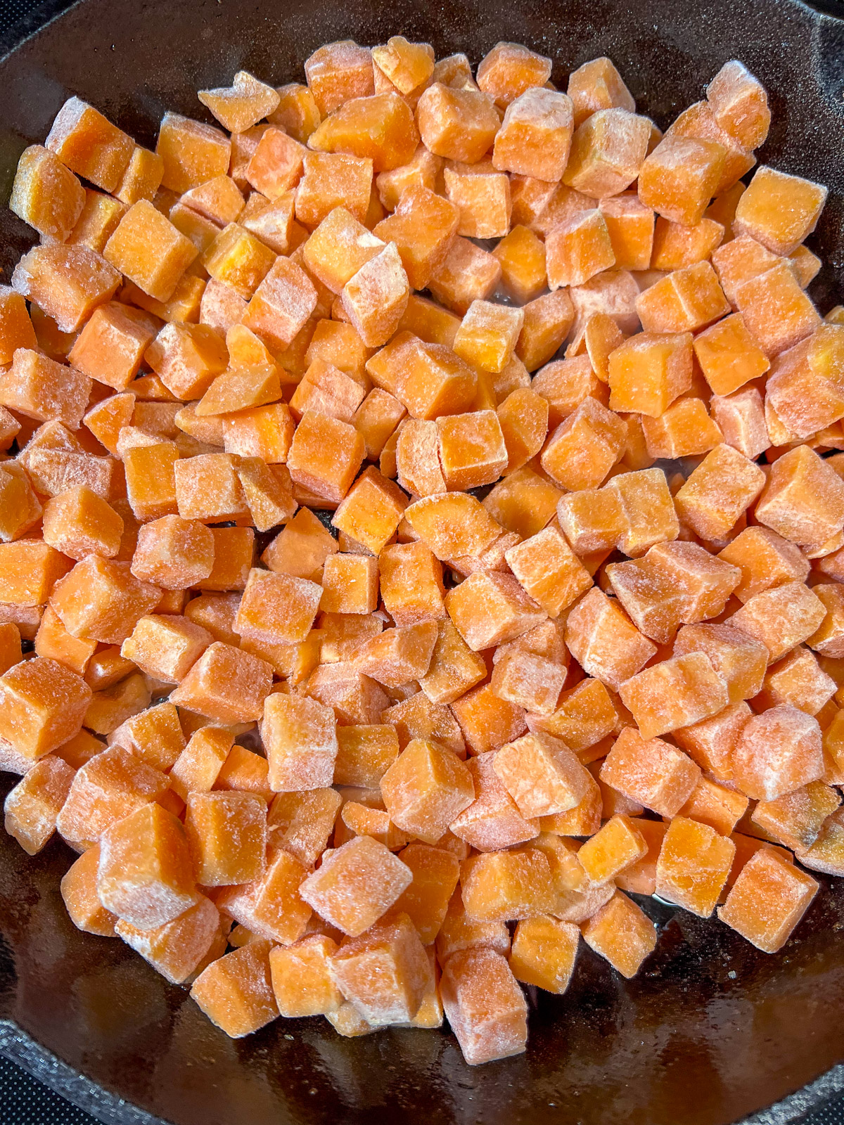 Cubed sweet potatoes added to the skillet with onions and bacon.