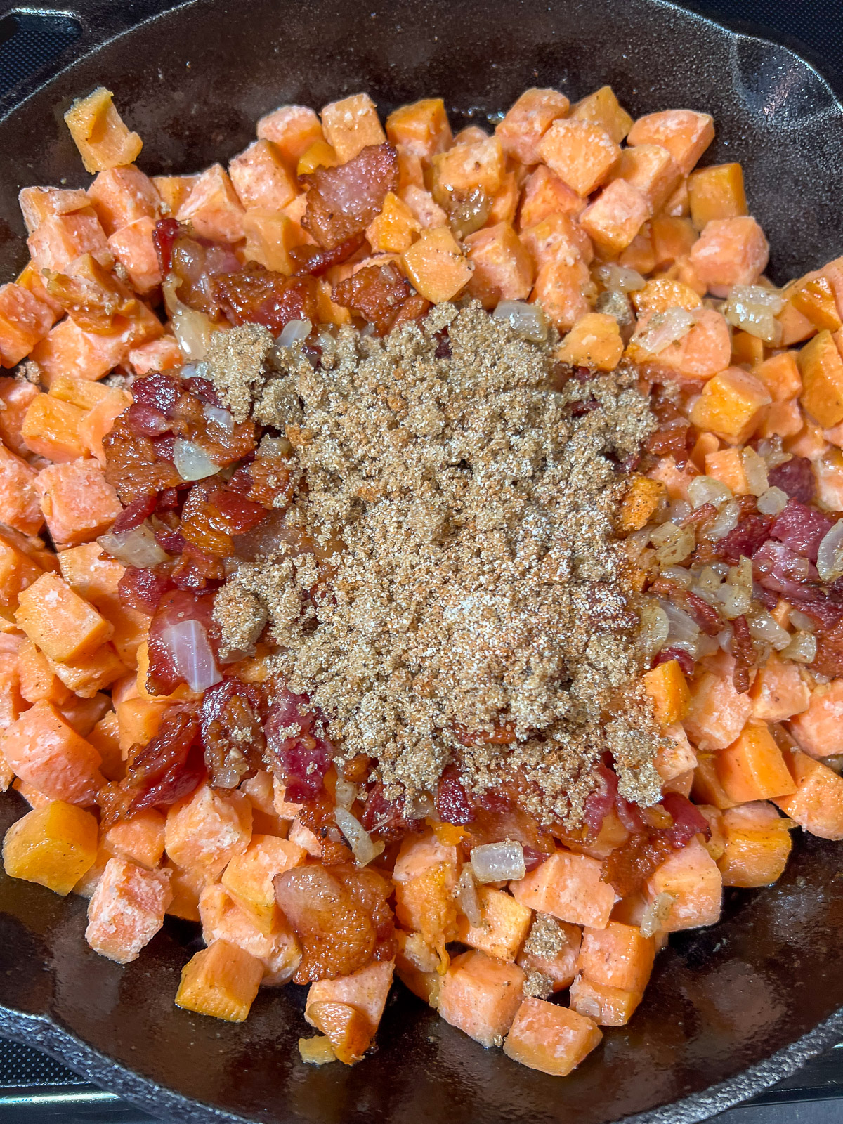 Sweet potato hash seasoned with brown sugar paprika and garlic in a cast iron skillet.