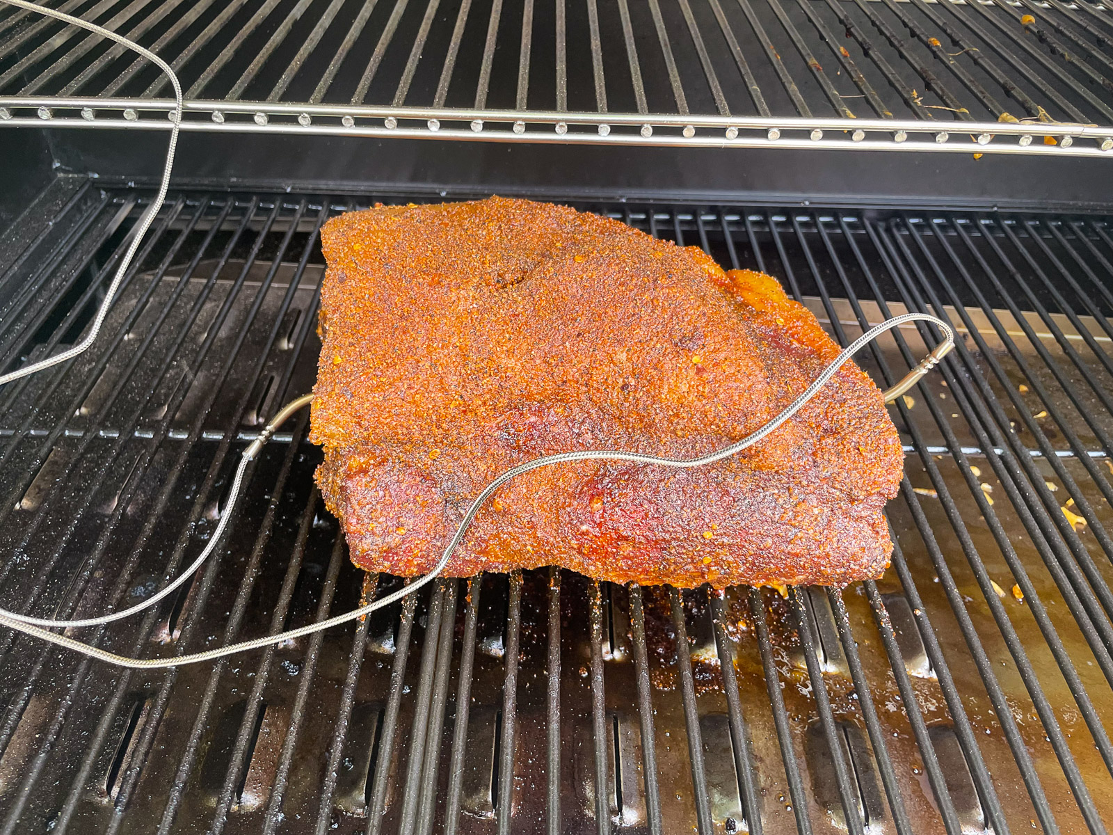 Rubbed pork butt on the smoker with meat thermometer probes.