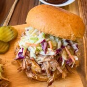 Smoked pulled pork sandwich with coleslaw and BBQ sauce.