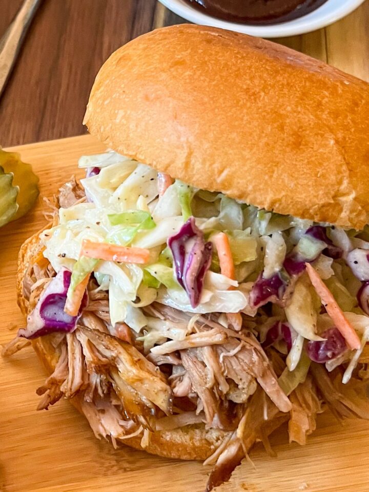 Smoked pulled pork sandwich with coleslaw and BBQ sauce.