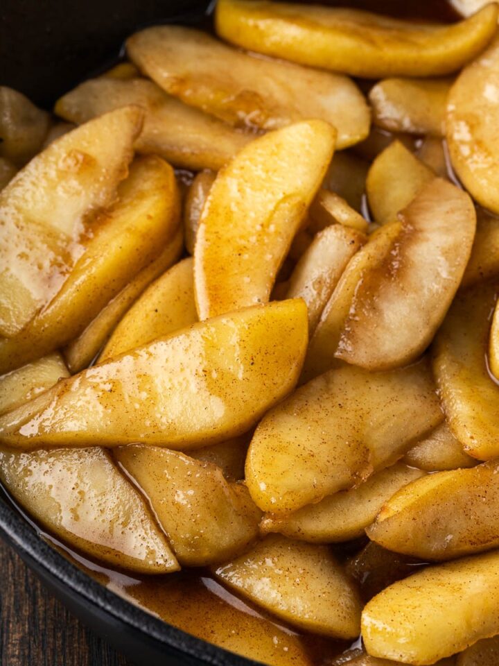 cast iron cinnamon apples in a skillet with golden brown sugar glaze