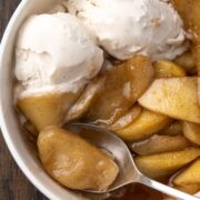 bowl of cast iron cinnamon apples topped with vanilla ice cream