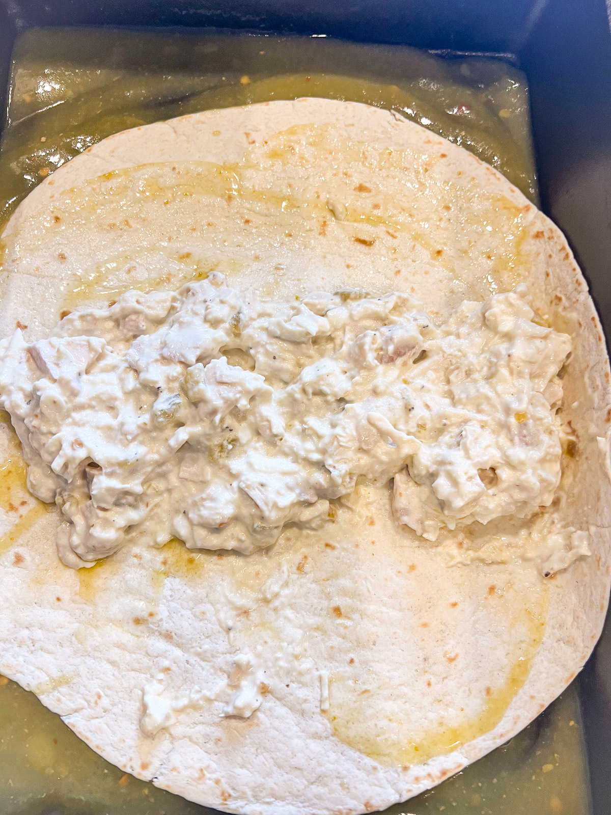 Rolling green chile chicken filling inside flour tortillas