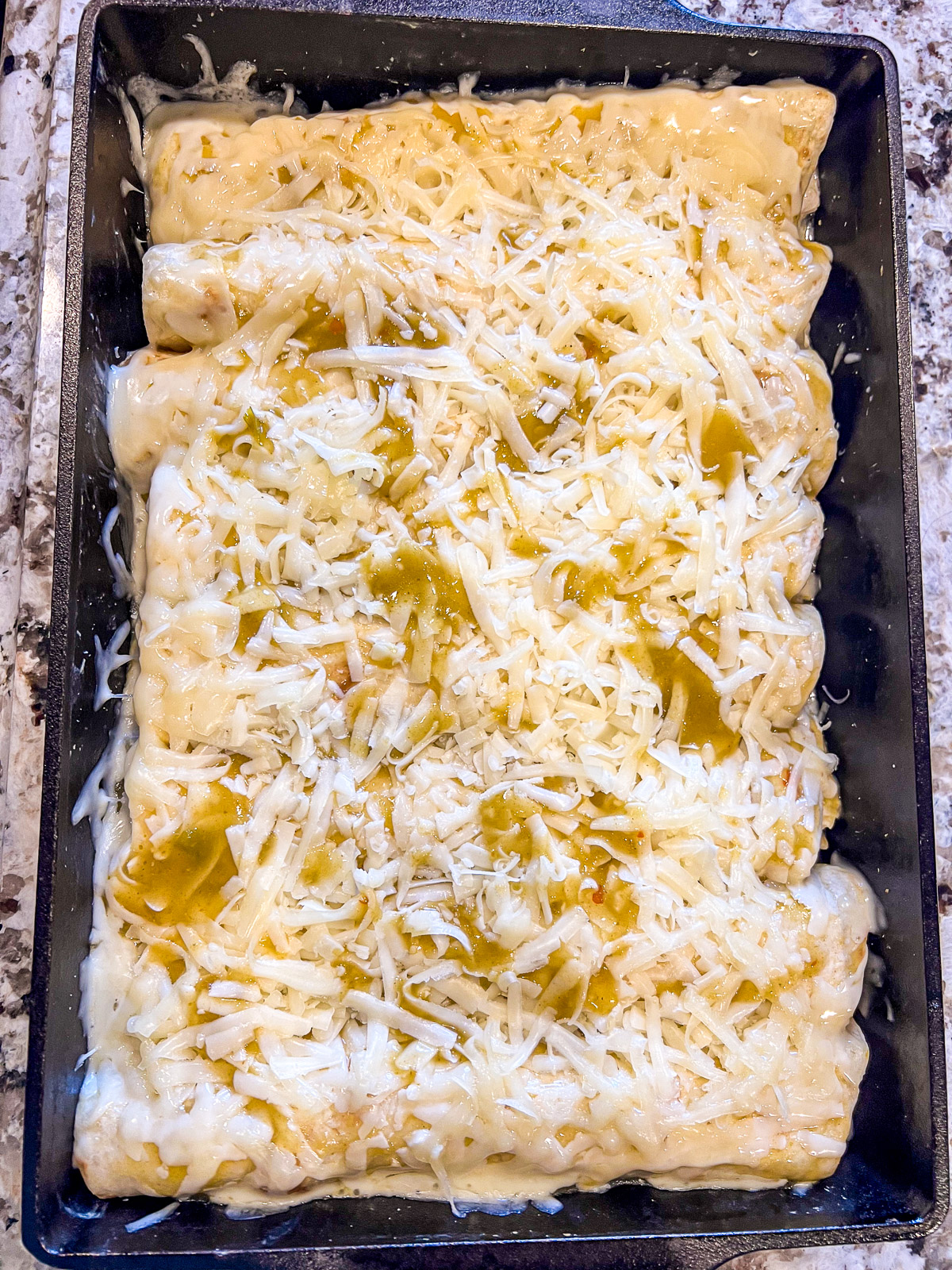 Rolled enchiladas arranged seam-side down in a baking dish