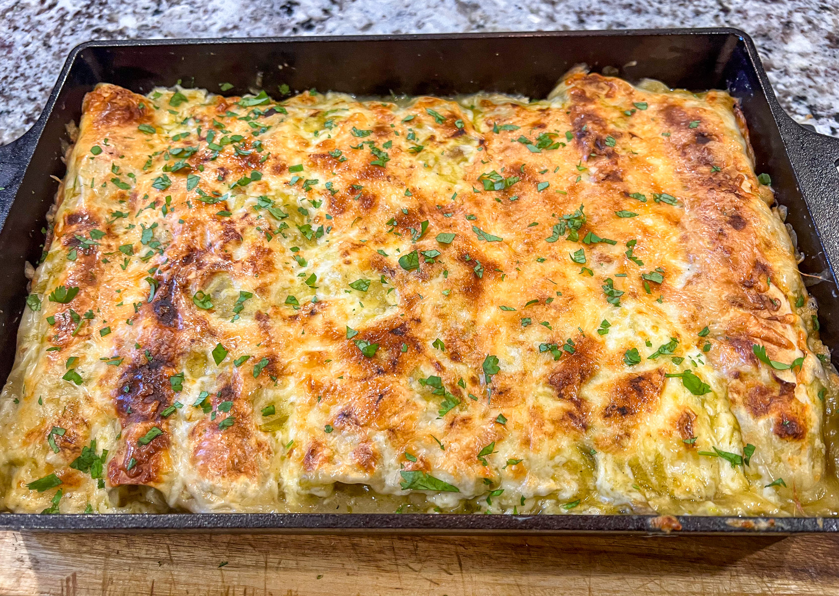 Baked creamy green chile chicken enchiladas golden and bubbly from the oven