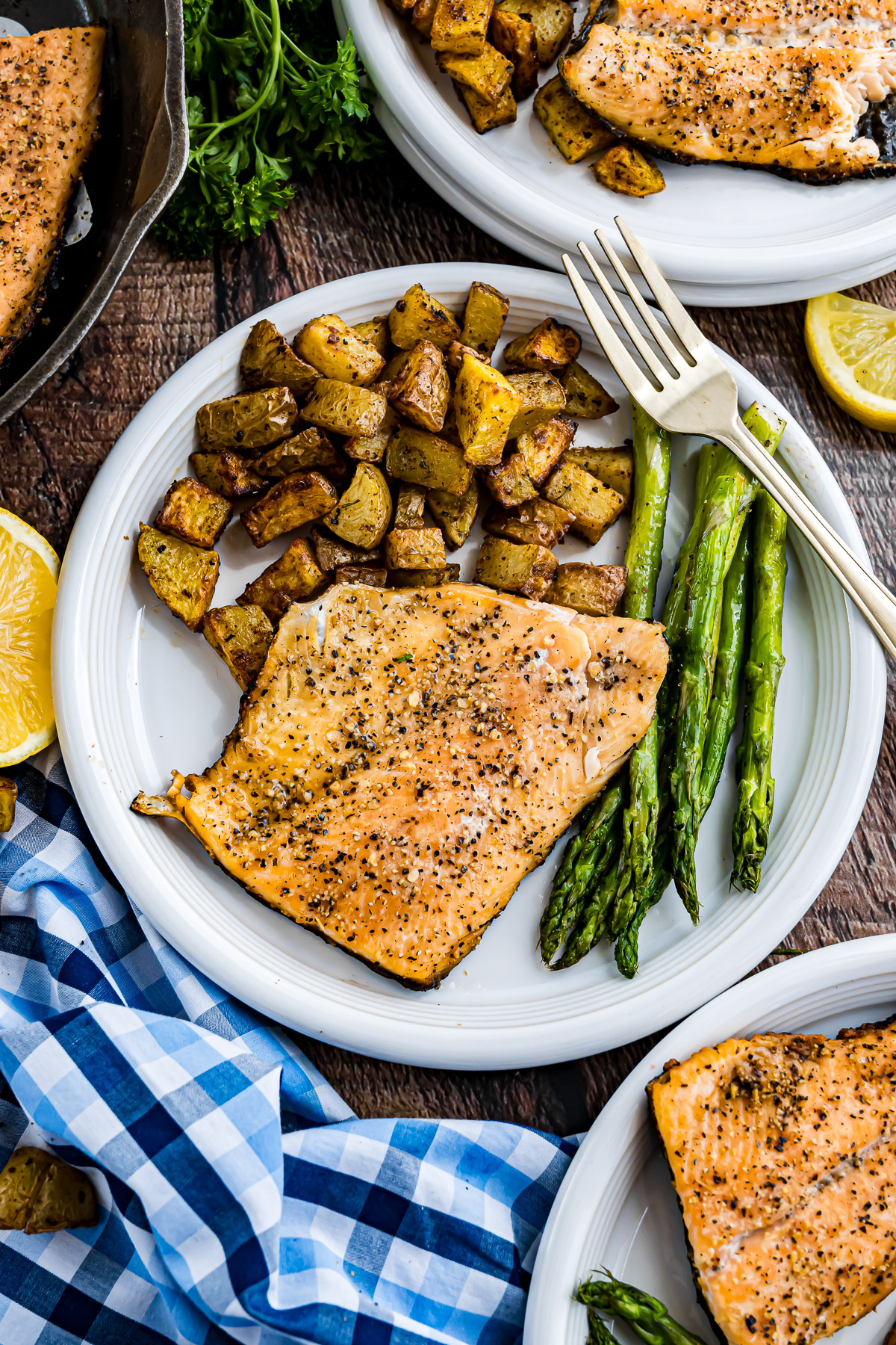 Grilled rainbow trout dinner table with plated fillets, skillet fried potatoes, and roasted asparagus
