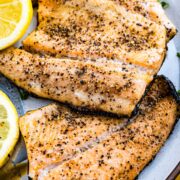 Grilled rainbow trout recipe with lemon pepper seasoning on a plate with lemon slices