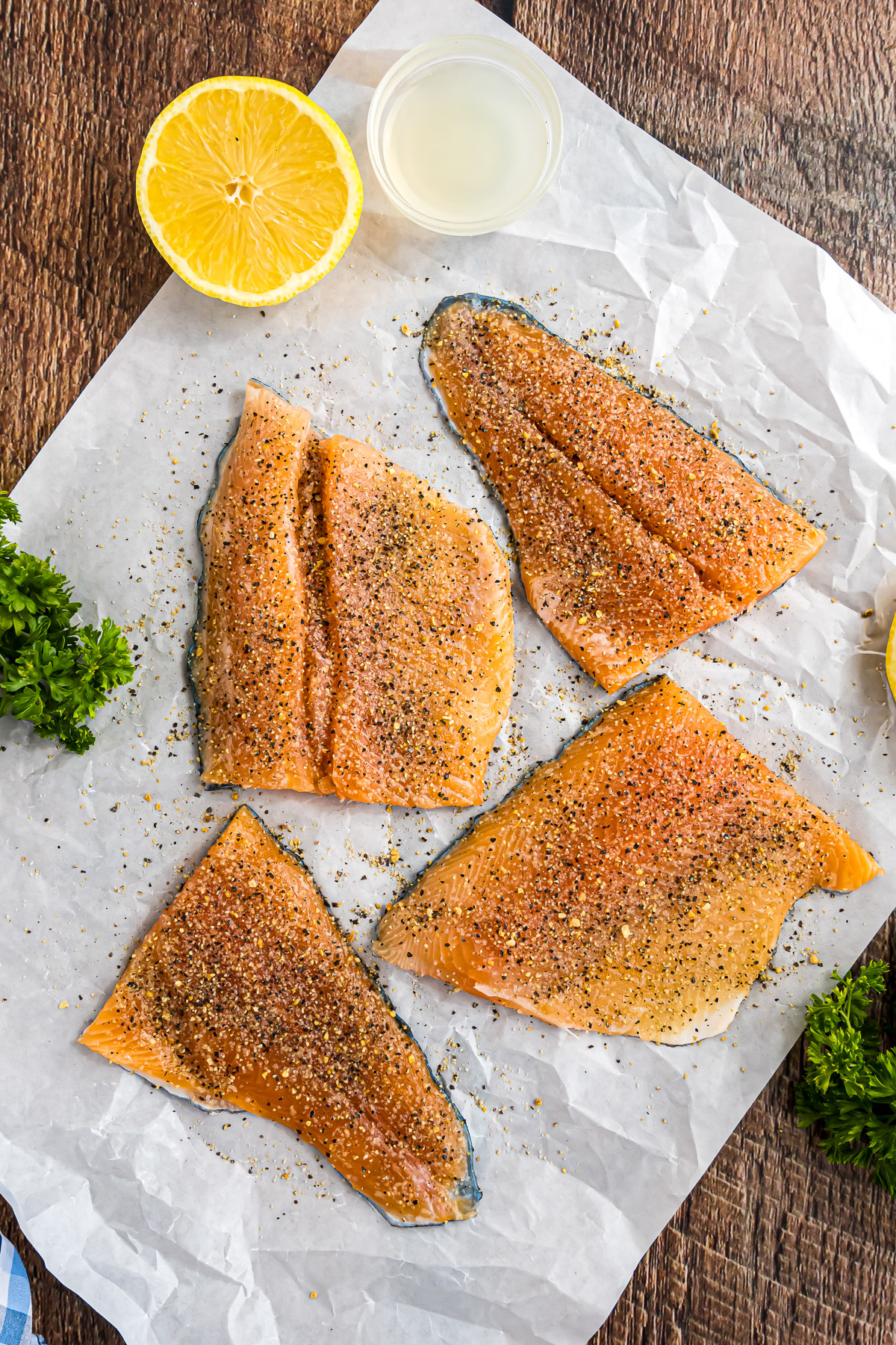 Rainbow trout fillets seasoned with lemon pepper on parchment paper