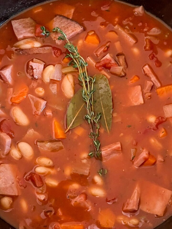 Dutch oven ham and bean soup with tomatoes in a cast iron pot