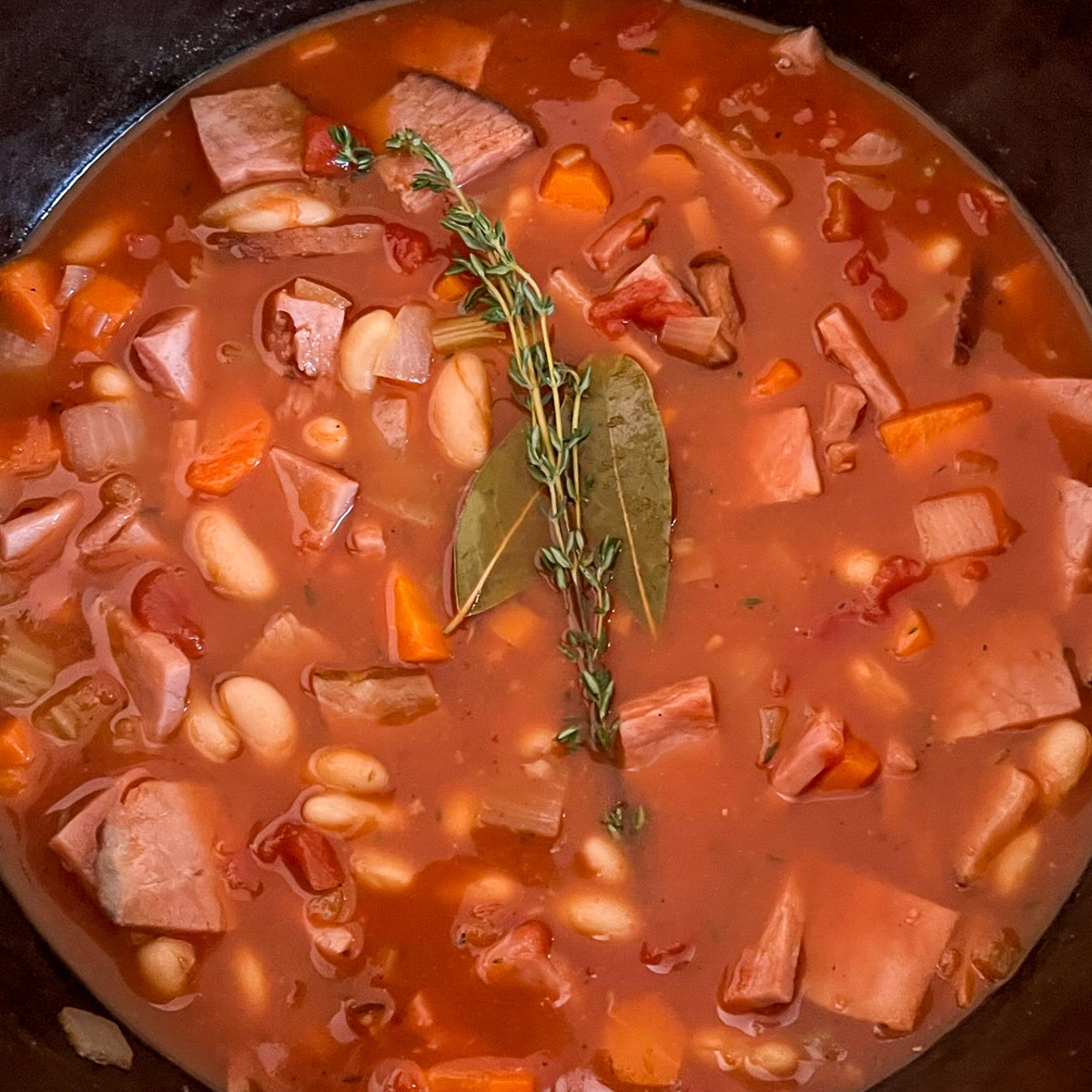 Dutch oven ham and bean soup with tomatoes in a cast iron pot