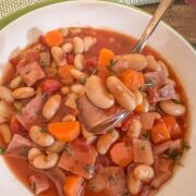 Ham and bean soup with tomatoes in a white bowl