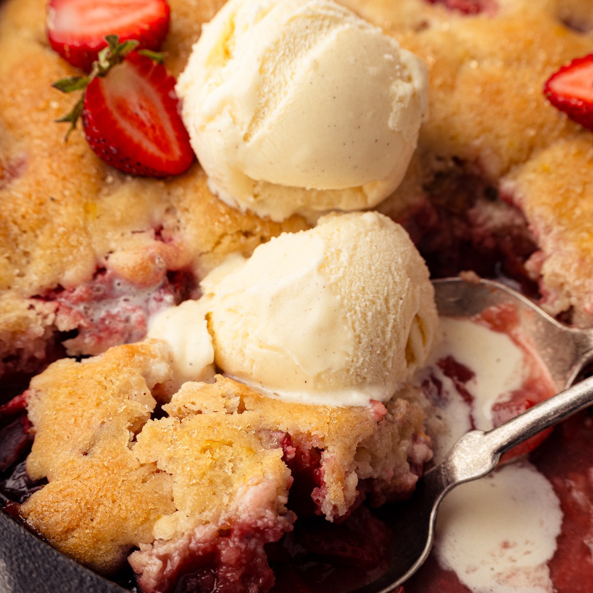 Skillet strawberry rhubarb cobbler with vanilla ice cream in cast iron