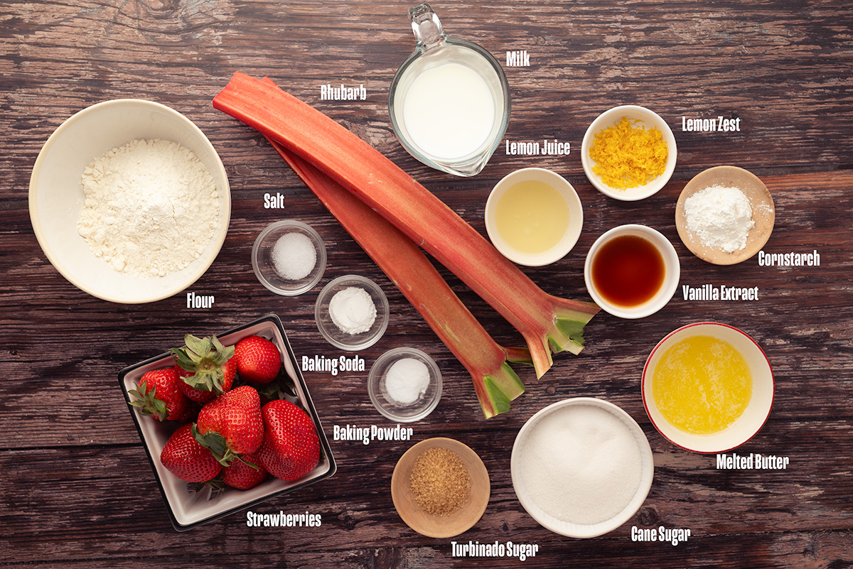 Ingredients for skillet strawberry rhubarb cobbler laid out on a wooden surface