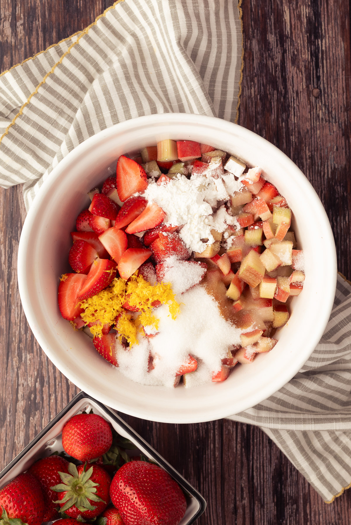 Strawberries and rhubarb in a bowl with sugar cornstarch and lemon zest
