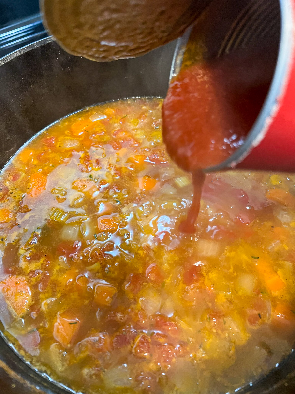 Stirring ham and bean soup in a Dutch oven